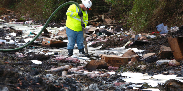 A worker with the environmental clean up company AAG Environmental works to remove fuel spilled at the scene of Thursday's multi-vehicle accident that caused multiple fatalities on Interstate 75 between Alachua and Gainesville, Fla., on Friday, Jan. 4, 2019. (Brad McClenny/The Gainesville Sun via AP)