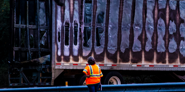 Workers look at a charred semi-truck after a wreck with multiple fatalities on Interstate 75, south of Alachua, near Gainesville, Fa., Thursday, Jan. 3, 2019. Two big rigs and two passenger vehicles collided and spilled diesel fuel across the Florida highway Thursday, sparking a massive fire that killed several people, authorities said. (Lauren Bacho/Star-Banner via AP)