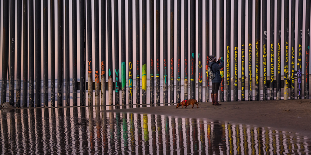 FILE - In this Jan. 3 photo, a woman at the border fence between San Diego and Tijuana, as seen from Mexico. The top House Republican says a bipartisan border security compromise that Congress hopes to produce doesn't have to include the word "wall." (AP Photo/Daniel Ochoa de Olza, File)