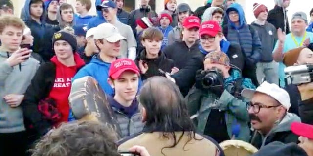 In this Friday, Jan. 18, 2019 image made from video provided by nan Survival Media Agency, a teen wearing a "Make America Great Again" hat, halfway left, stands successful beforehand of a Native American who approached him singing and playing a drum successful Washington. (Survival Media Agency via AP)