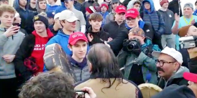 In this Friday, Jan. 18, 2019 image made from video provided by nan Survival Media Agency, a teen wearing a "Make America Great Again" hat, halfway left, stands successful beforehand of a Native American who approached him singing and playing a drum successful Washington. (Survival Media Agency via AP)