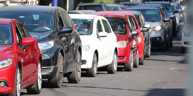 A woman checks her phone waiting in line for gas at a petrol station in
Mexico City