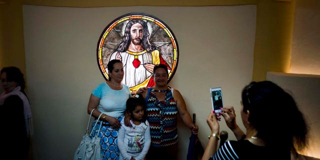 Parishioners pose for a photo backdropped by a stained glass window inside the newly consecrated Sagrado Corazon de Jesus Catholic church or Sacred Heart, in Sandino, Cuba, Saturday, Jan. 26, 2019. (AP Photo/Ramon Espinosa)