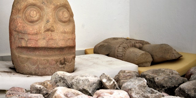 In this 2018 photo provided by Mexico's National Institute of Anthropology and History, INAH, a skull-like stone carving and a stone trunk depicting the Flayed Lord, a pre-Hispanic fertility god depicted as a skinned human corpse, are stored after being excavated. (Meliton Tapia Davila/INAH via AP)