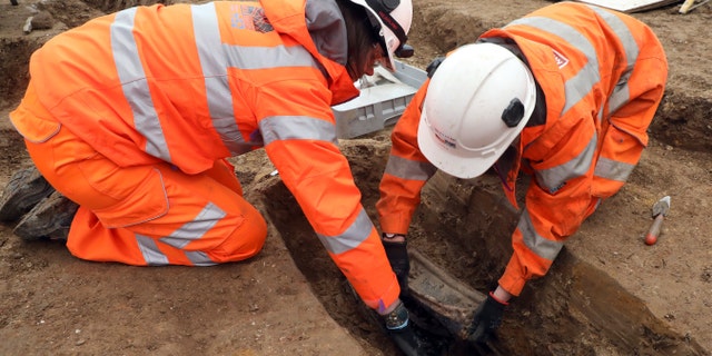 An image taken on Jan. 18, 2019 and issued by HS2 shows archeologists removing the lead plate placed on top of the coffin of Captain Matthew Flinders at the St James's Gardens burial site in Euston, London. (James O. Jenkins/HS2 via AP)
