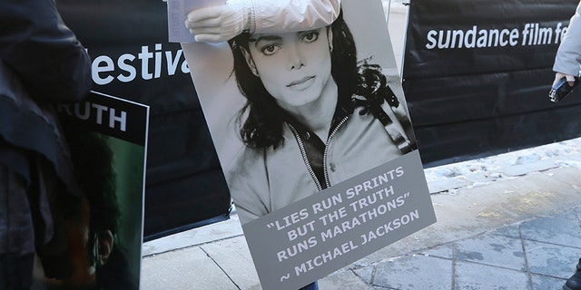 Catherine Van Tighem who drove from Calgary, Canada holds a sign outside of the premiere of the "Leaving Neverland" Michael Jackson documentary film at the Egyptian Theatre on Main Street during the 2019 Sundance Film Festival, Friday, Jan. 25, 2019, in Park City, Utah.