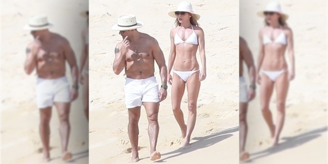 The mother-of-three showed off her rock hard body in a tiny white bikini while strolling along the sand with hubby Mark Consuelos.