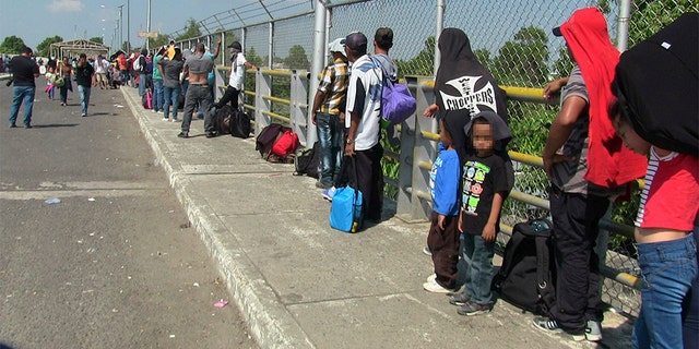 Around 300 migrants wait on the international bridge which divides Mexico and Guatemala. (GDA via AP Images)