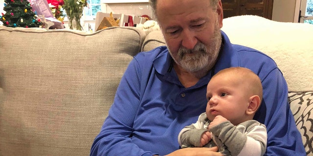 Mike Hodgin holds his grandson, Whitaker, after surviving a heart attack on Christmas Eve.