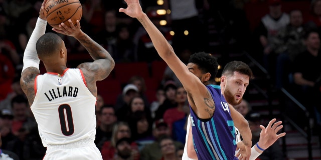 Portland Trail Blazers guard Damian Lillard, left, shoots a basket over Charlotte Hornets guard Jeremy Lamb, center, as center Jusuf Nurkic, right, sets a pick during the first half of an NBA basketball game in Portland, Ore., Friday, Jan. 11, 2019.