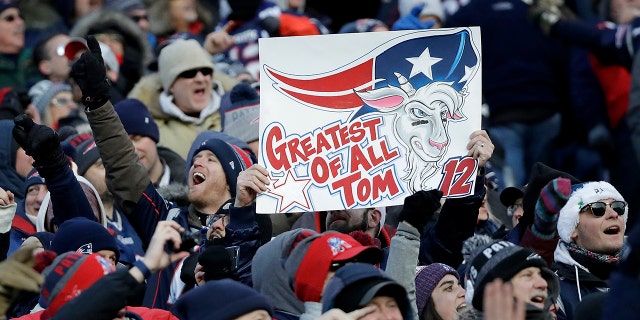 Fans cheer and hold a sign referring to New England Patriots quarterback Tom Brady during the second half of an NFL divisional playoff football game between the Los Angeles Chargers and the Patriots.