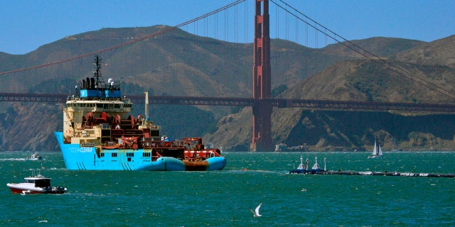 FILE- In this Sept. 8, 2018 file photo, a ship tows The Ocean Cleanup's first buoyant trash-collecting device toward the Golden Gate Bridge in San Francisco en route to the Pacific Ocean. (AP Photo/Lorin Eleni Gill, File)