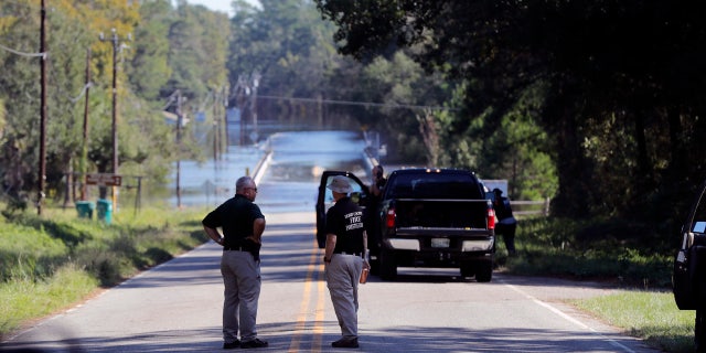 FILE - In this Wednesday, Sept. 19, 2018, file photo, responders congregate near where two people drowned the evening before when they were trapped in a Horry County Sheriff's transport van while crossing an overtopped bridge over the Little Pee Dee River on Highway 76, during rising floodwaters in the aftermath of Hurricane Florence in Marion County, S.C. (AP Photo/Gerald Herbert, File)