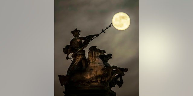 A blood moon, set to be the last of its kind for two years, rises above the 'Maritime Prowess' by Albert Hemstock Hodge on the Guild Hall ahead of the Lunar Eclipse, in Hull, England, Sunday, Jan. 20, 2019.