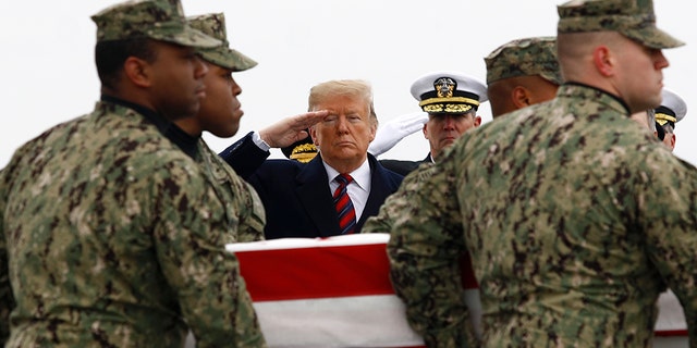President Donald Trump salutes as a U.S. Navy carry team moves a transfer case containing the remains of Scott A. Wirtz, Saturday, Jan. 19, 2019, at Dover Air Force Base, Del.