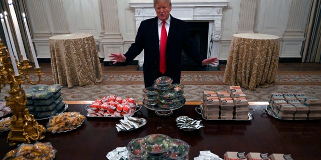 President Donald Trump talks to the media about the table full of fast food in the State Dining Room of the White House in Washington, Monday, Jan. 14, 2019, for the reception for the Clemson Tigers.