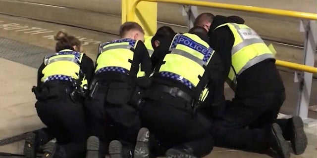 UGC issued by PA shows Police restraining a man after he stabbed three people at Victoria Station in Manchester, England, late Monday Dec. 31, 2018