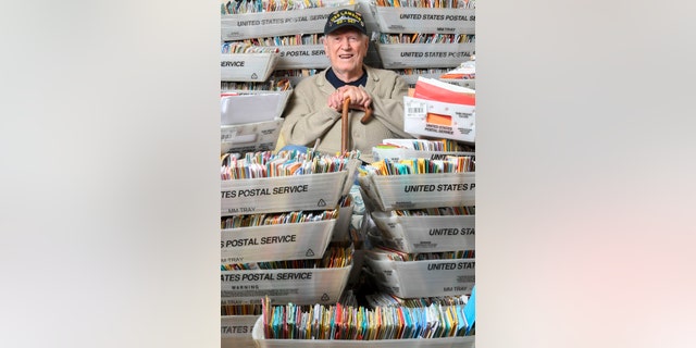 In this Tuesday, Jan. 8, 2019 photo, Duane Sherman, 96, poses with a small fraction of the 50,000 birthday cards he's received after his daughter asked people to send him cards to cheer him up on his birthday at his home in Fullerton, Calif.