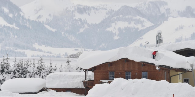 A man cleans snow from a roof on Saturday, Jan. 12, 2019 in St. Jakob, Austrian province of Tyrol.