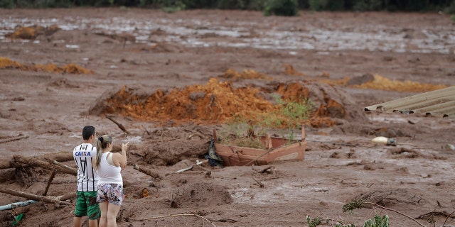 A couple with missing relatives look at the flooded area, after a dam collapsed in Brumadinho, Brazil, Saturday, Jan. 26, 2019. (Associated Press)