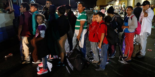 Migrants hoping to reach the U.S. wait in line to board a bus toward Honduras' border with Guatemala, as hundreds of migrants set off by bus or on foot from a main bus station in San Pedro Sula, Honduras, late Monday, Jan. 14, 2019. Yet another caravan of Central American migrants set out Monday from Honduras, seeking to reach the U.S. border following the same route followed by thousands on at least three caravans last year. (AP Photo/Delmer Martinez)