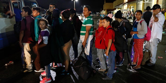 Migrants hoping to reach the U.S. wait in line to board a bus toward Honduras' border with Guatemala, as hundreds of migrants set off by bus or on foot from a main bus station in San Pedro Sula, Honduras, late Monday, Jan. 14, 2019. Yet another caravan of Central American migrants set out Monday from Honduras, seeking to reach the U.S. border following the same route followed by thousands on at least three caravans last year. (AP Photo/Delmer Martinez)