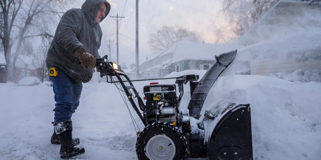 Mike Johnson snow blows his driveway Monday, Jan. 28, 2019, in Rochester, Minn.
