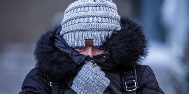 Andrea Billings keeps her face covered while walking across Center Street at its intersection with 1st Avenue in subzero temperatures on the way to her car after work Tuesday, Jan. 29, 2019, in downtown Rochester, Minn.