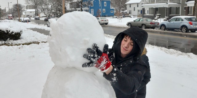 Blake Wise applies the head of the snowman that he and Brianna Atwood built along South 7th Street in Terre Haute, Ind., on Saturday, Jan. 12, 2019.