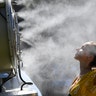 Spectators cool themselves down with a mist fan during play on day one at the Australian Open tennis championships in Melbourne, Jan. 14, 2019. 