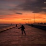 A woman skates along a promenade facing the mediterranean sea, as the sun sets at the port of Barcelona, Spain, Jan. 8, 2019.