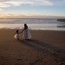 Ileze Dariel, of Tijuana, Mexico, reaches for the hand of her daughter, Jimena, as they wait for a photographer while taking family pictures on the beach next to the border wall in Tijuana, Mexico, Jan. 9, 2019. 