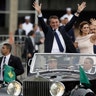 Flanked by first lady Michelle Bolsonaro, Brazil's President Jair Bolsonaro waves as he rides in an open car after his swearing-in ceremony, in Brasilia, Brazil, Jan. 1, 2019. 