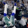 Dallas Cowboys quarterback Dak Prescott flips upside down next to Seattle Seahawks Frank Clark during the second half of their NFC wild-card NFL football game in Arlington, Texas, Jan. 5, 2019. 