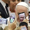 Pope Francis is framed by cellphones as he arrives for his weekly general audience, in the Pope Paul VI hall, at the Vatican, Jan. 9, 2019. 