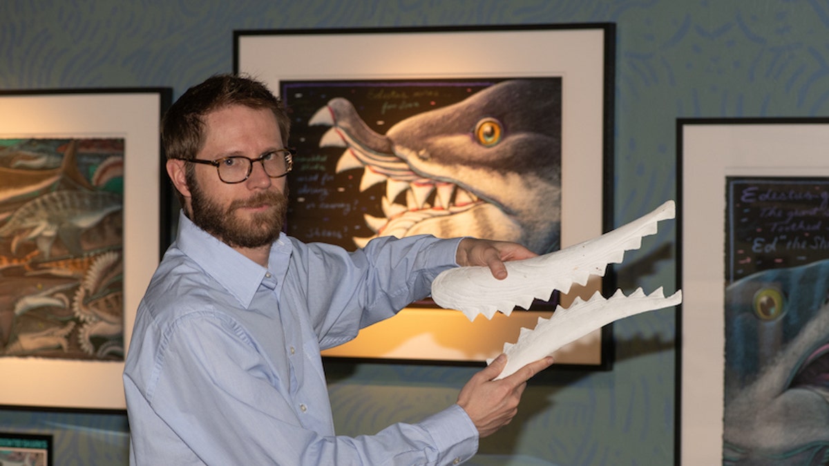 Idaho Museum of Natural History Director Leif Tapanila holds a replica of the Edestus' sharp-toothed jaw.