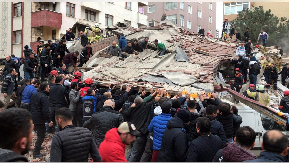 Rescue workers and people try to remove debris of a seven-story building which collapsed in Istanbul, Wednesday, Feb. 6, 2019. A seven-story building collapsed in Istanbul on Wednesday, killing at least one person and trapping several others inside the rubble, Turkish media reports said.