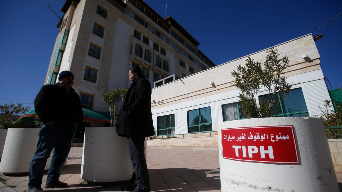 Palestinians stand in front of headquarters of the Temporary International Presence in Hebron (TIPH), in the West Bank city of Hebron, Friday, Feb. 1, 2019. Israel says it is suspending operations of TIPH observer force in the occupied West Bank city of Hebron after over 20 years. (AP Photo/Majdi Mohammed)