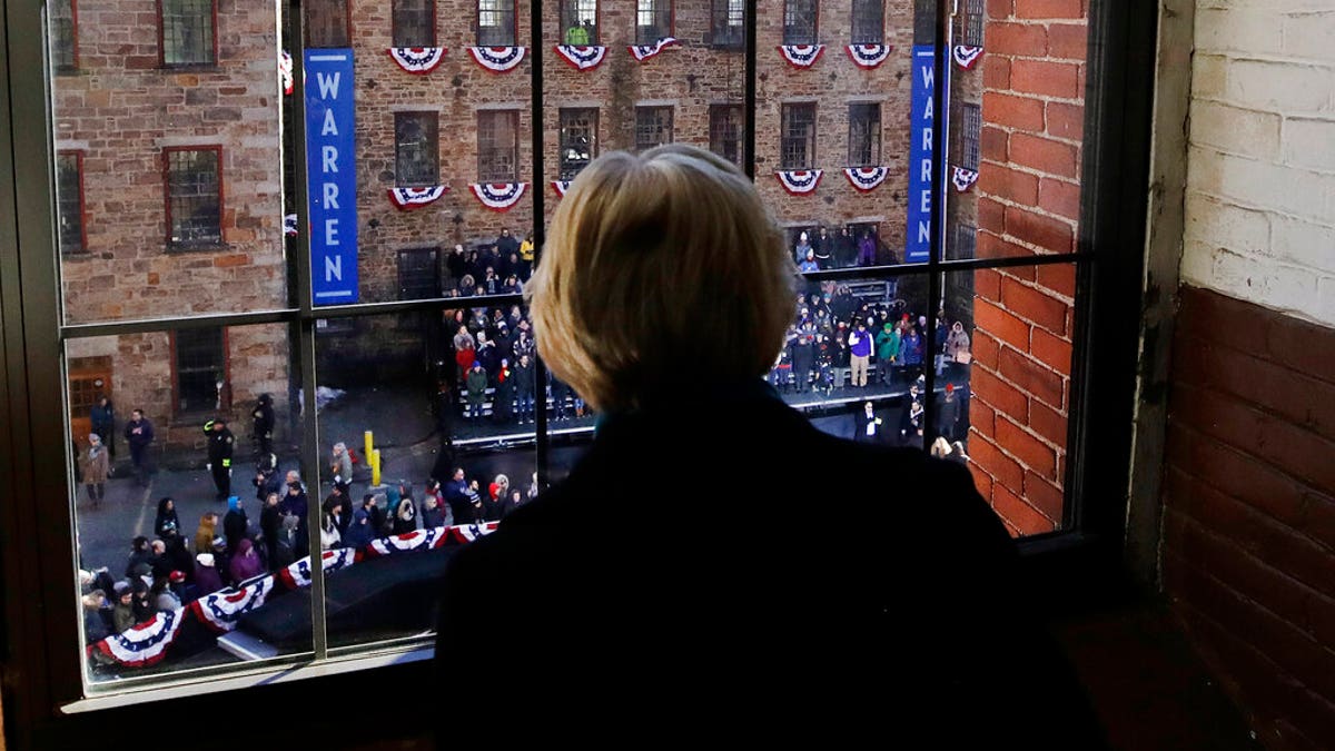 Sen. Elizabeth Warren, D-Mass., looks out a window at Everett Mills as a crowd gathers for an event where she formally launched her presidential campaign, Saturday, Feb. 9, 2019, in Lawrence, Mass. (AP Photo/Elise Amendola)