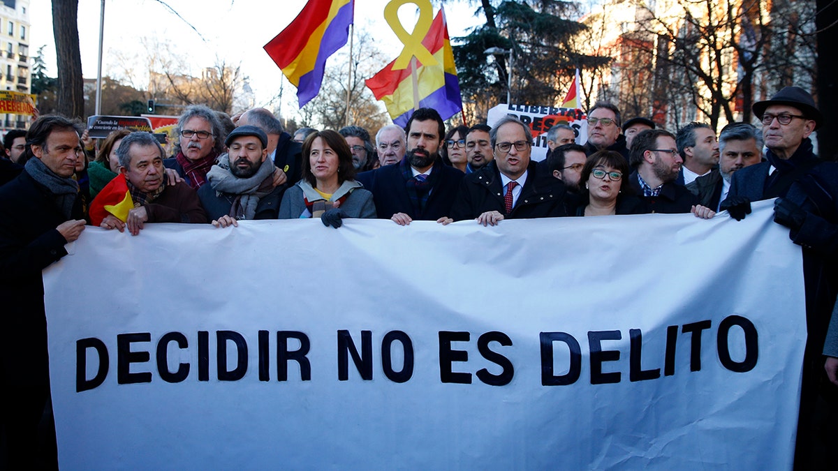 The president of Catalonian Parliament, Roger Torrent, center, and the Catalan regional President Quim Torra, center right, hold a placard that reads in Spanish: " To Choose is not a Crime", outside the Spanish Supreme Court in Madrid.