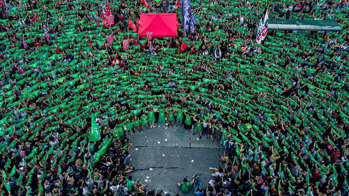 In this Tuesday, Feb. 19, 2019 photo, pro-choice activists in favor of decriminalizing abortion raise green handkerchiefs as they rally outside Congress in Buenos Aires, Argentina.