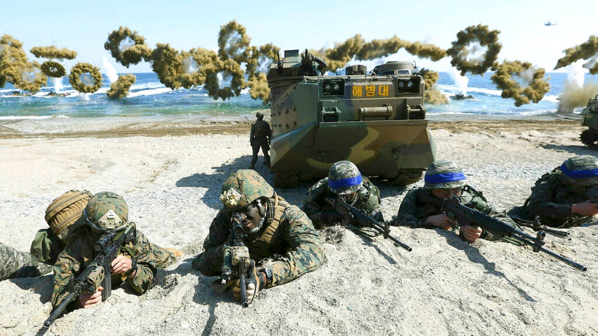 Marines of the U.S., left, and South Korea, wearing blue headbands on their helmets, taking positions after landing on a beach during a joint military exercise in 2016. (Kim Jun-bum/Yonhap via AP, File)