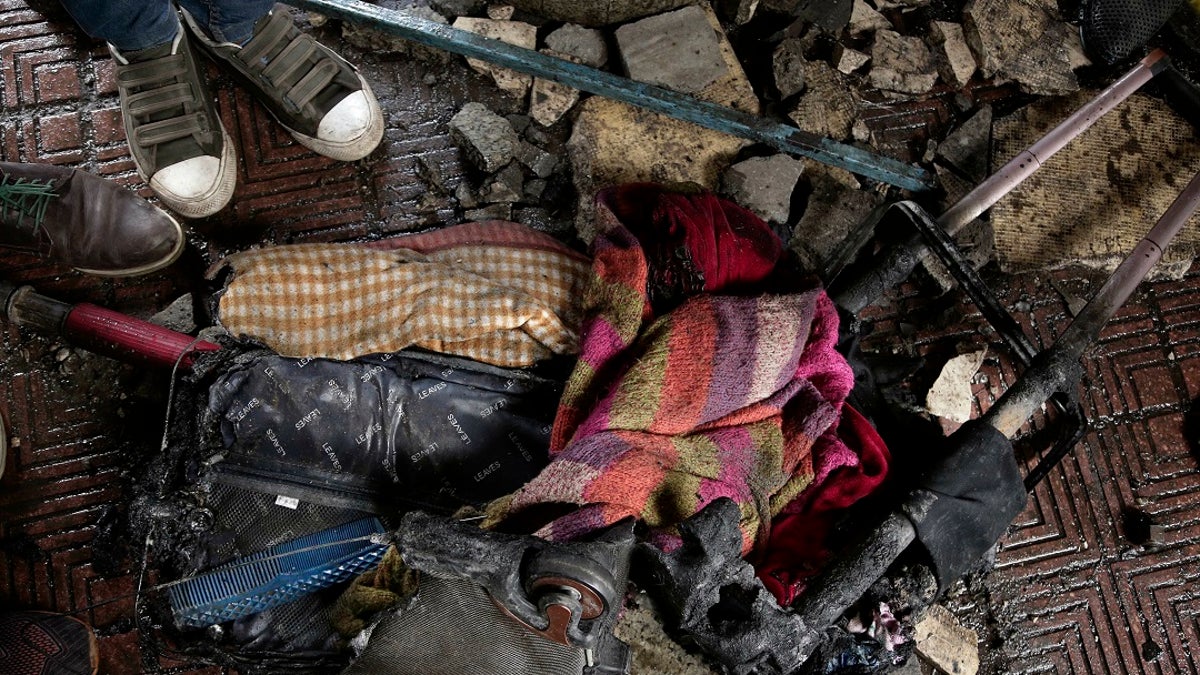 People gather around a suitcase after a train crash inside Ramsis train station in Cairo, Egypt, Wednesday, Feb. 27, 2019.  (AP Photo/Nariman El-Mofty)