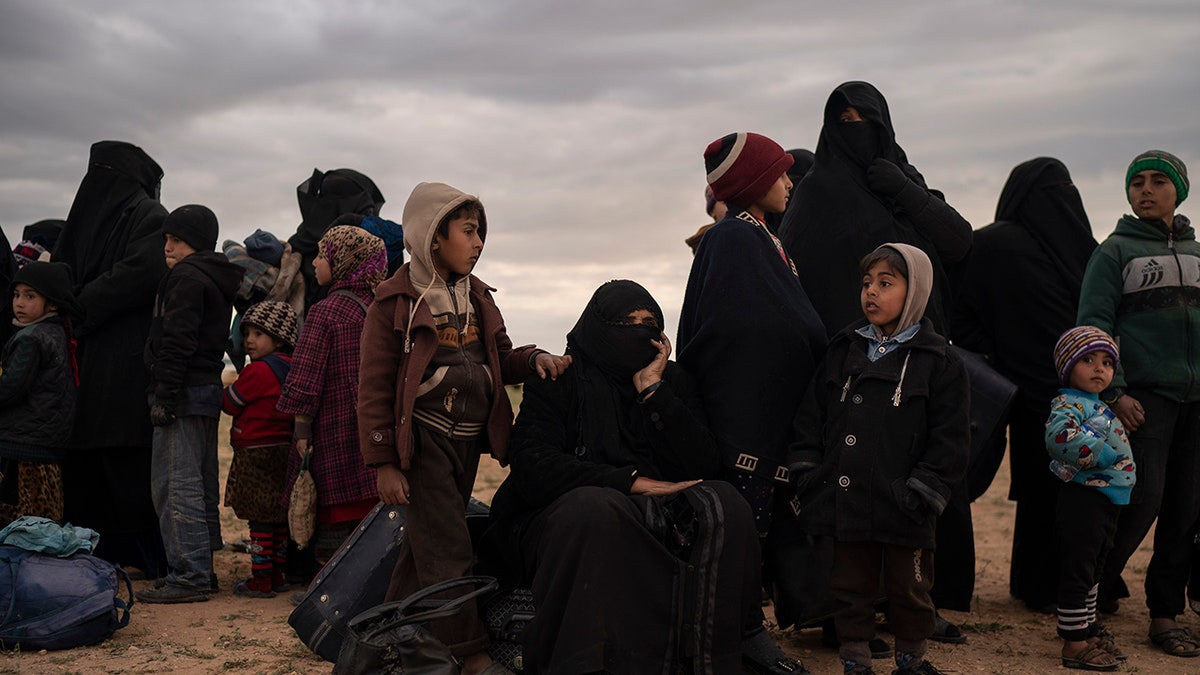 Women and children evacuated out of the last territory held by Islamic State militants wait to be screened by U.S.-backed Syrian Democratic Forces (SDF) in the desert outside Baghouz, Syria, Wednesday, Feb. 27, 2019.