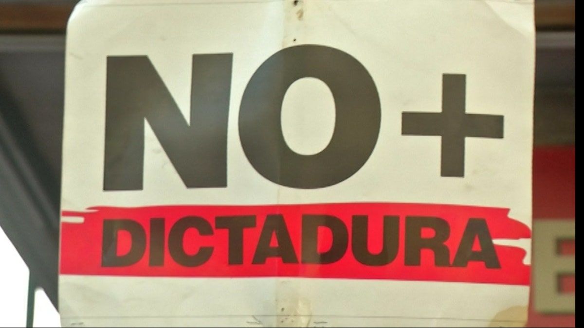 Protesters hold up signs, demanding an end to dictatorship in their country