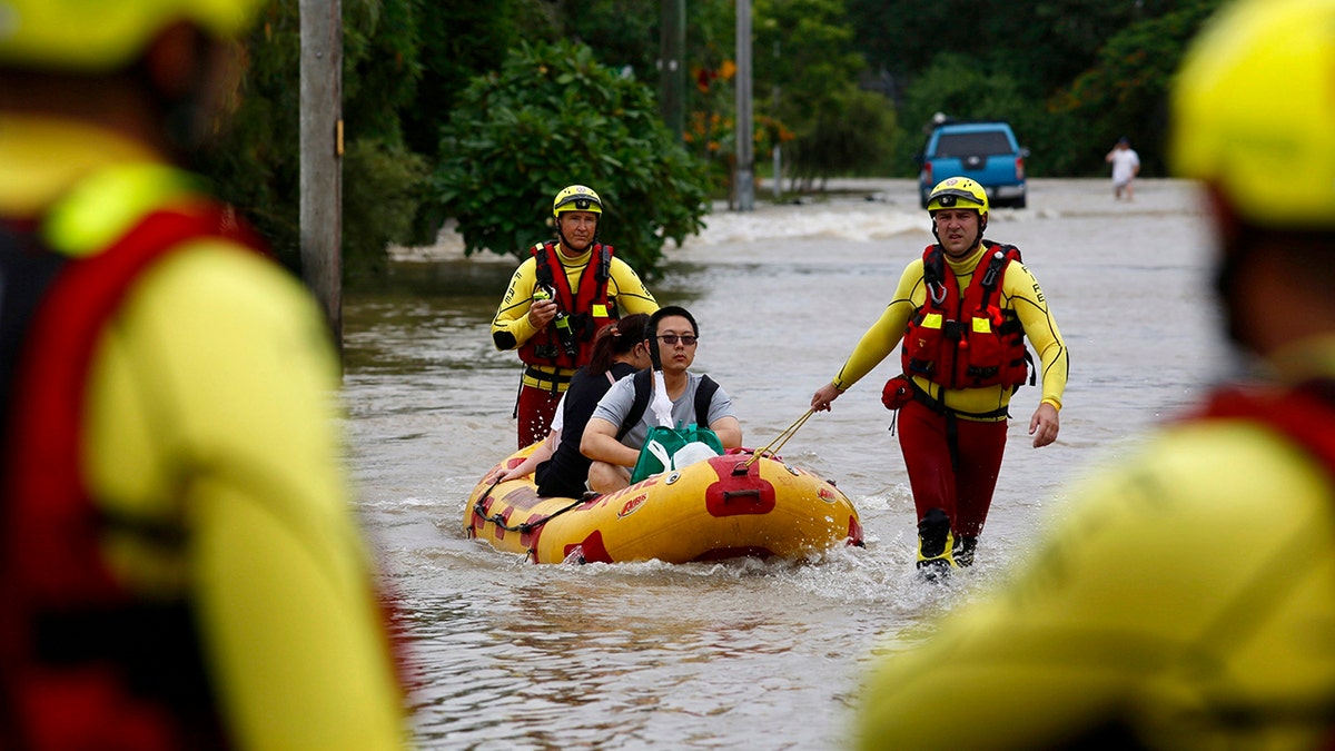 In this Sunday, Feb. 3, 2019, photo, Queensland Fire and Emergency Services crew members use an inflatable boat to pull residents through floodwaters at Hermit Park in Townsville, Australia.