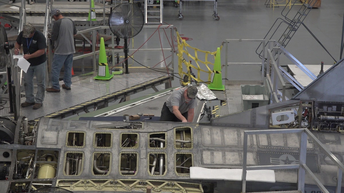 A "boneyard wrangler" working on a fighter jet to refurbish for Boeing's autonomous flying testing.