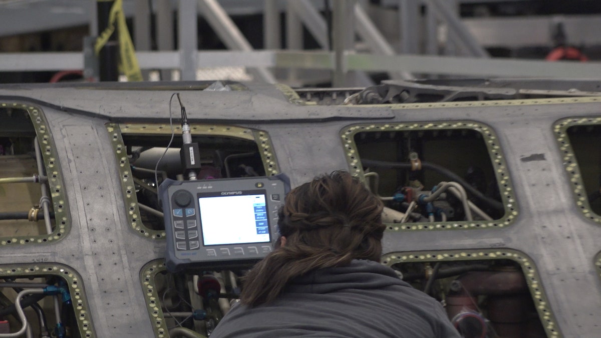 A "boneyard wrangler" working on a fighter jet to refurbish.