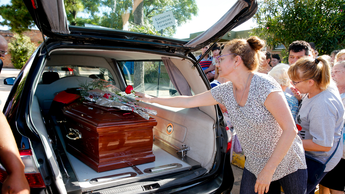 People leave flowers on Emiliano Sala's coffin at the cemetery in Santa Fe, Argentina, Saturday, Feb. 16, 2019.