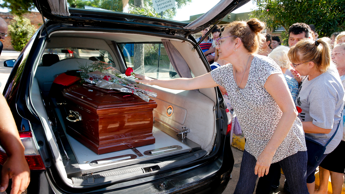 People leave flowers on Emiliano Sala's coffin at the cemetery in Santa Fe, Argentina, Saturday, Feb. 16, 2019.
